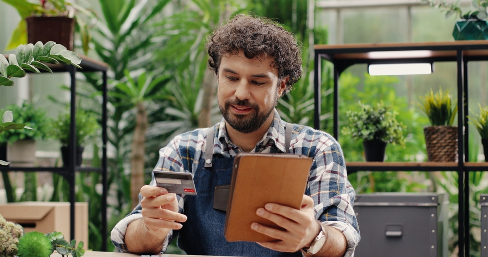 male greenhouse professional holding credit card during purchasing process