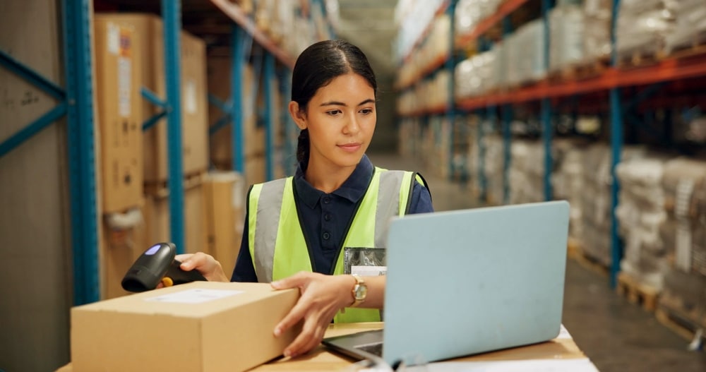 female warehouse worker using supply chain management computer in warehouse