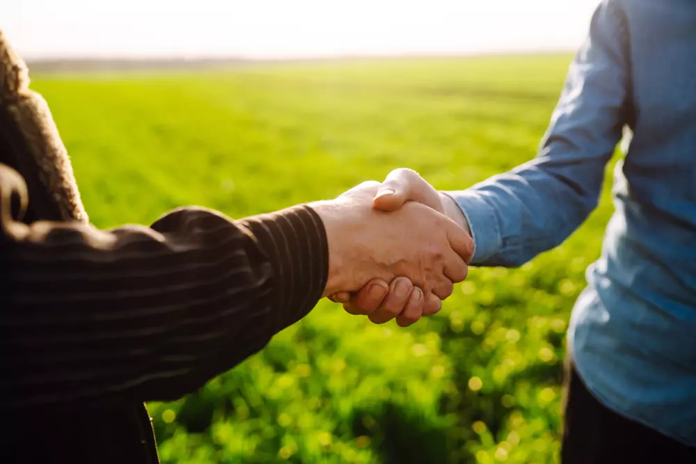 shaking hands with a green field in the background